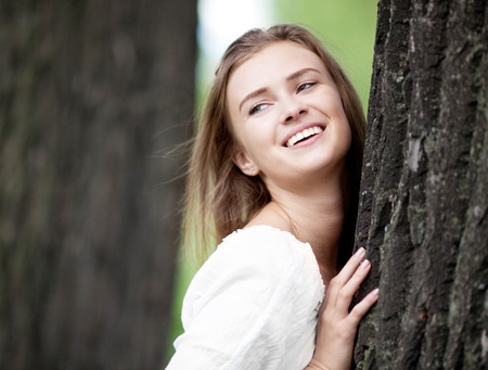 happy young woman standing near the tree  in the park  on a warm summer dayの写真素材