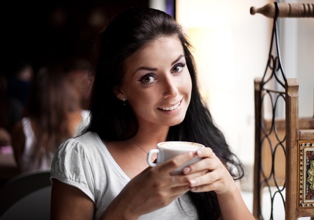 pretty young woman sitting in the cafe with a cup of teaの写真素材