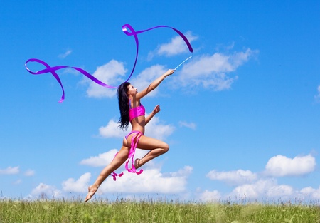 happy jumping young woman with a ribbon outdoor on a summer dayの写真素材