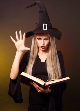 angry  blond witch with a book conjuring, against black and yellow backgroundの写真素材