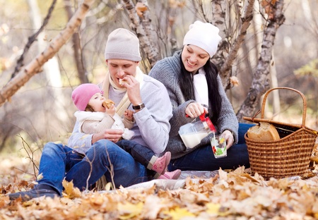 happy young family with their daughter spending time outdoor in the autumn park (focus on the man)の写真素材
