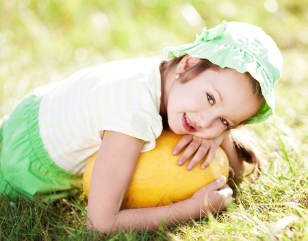 cute happy  little girl with melon on the grass in summertimeの写真素材