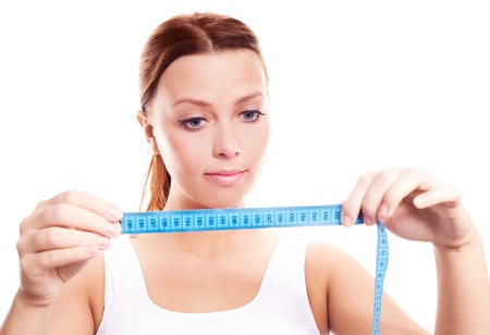 beautiful young woman looking at the measuring tape, isolated against white backgroundの写真素材