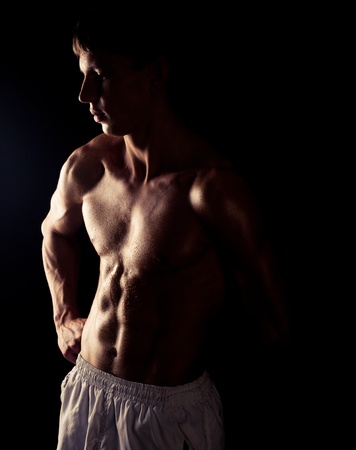 torso of young muscular man, isolated on black backgroundの写真素材
