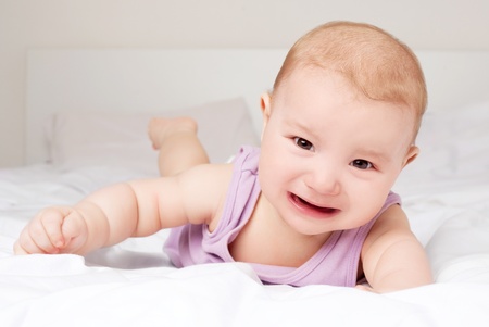 angry crying  six months old baby in bed at home
