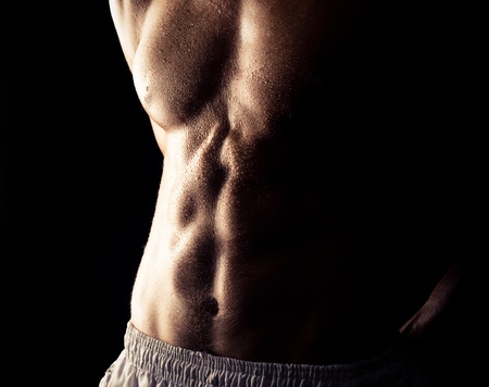 torso of young muscular man, isolated on black background