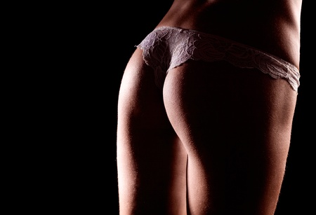 buttocks of a slim young woman, wearing white underwear with embroidery,  isolated on black studio backgroundの写真素材