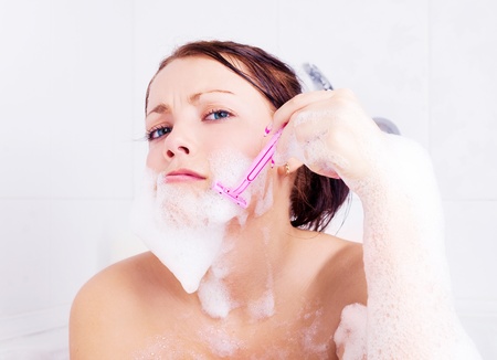 beautiful young brunette woman taking a  bath with foam and shaving の写真素材