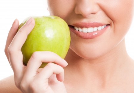 closeup of the face of a woman holding a green apple, isolated against white background closeup of the face of a woman holding a green apple, isolated against white background