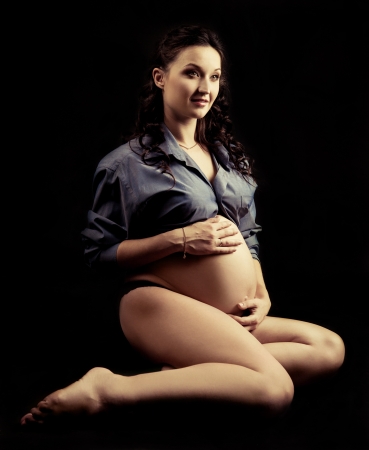 beautiful young pregnant woman, isolated on black studio backgroundの写真素材