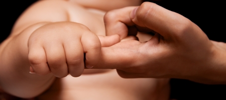 hands of mother and baby, against black studio backgroundの写真素材
