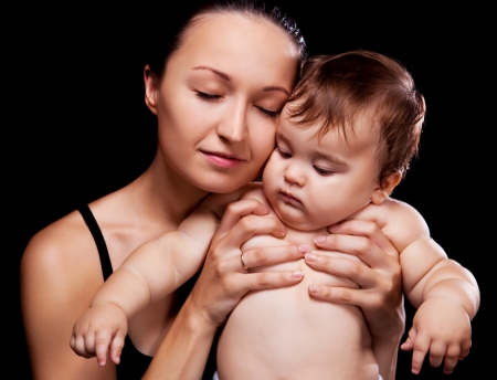 young mother and her baby in the studio, isolated on black backgroundの写真素材