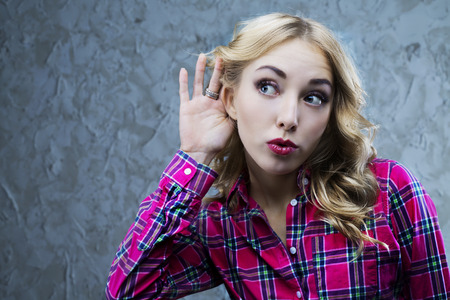 interested young blond woman listening to something, studio shotの写真素材