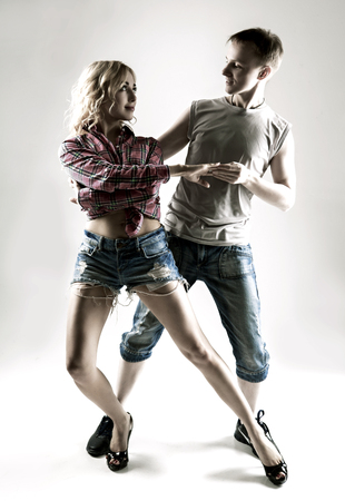 happy young couple dancing, against studio backgroundの写真素材