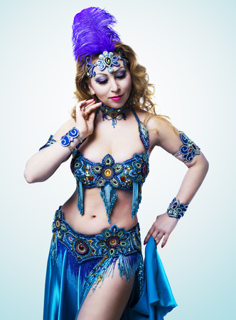 beautiful belly-dancer with long ginger hair and arabic makeup, isolated against ight blue studio backgroundの写真素材