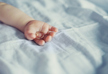 arm of a baby with a golden ring in bedの写真素材