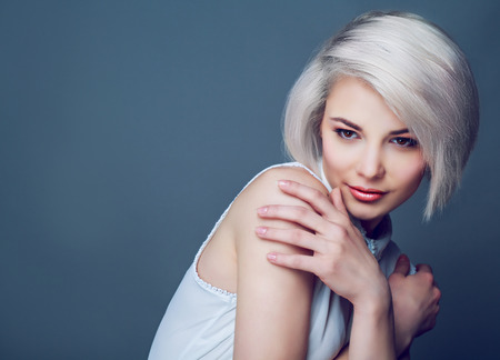 beautiful young blond woman with brown eyes against grey studio backgroundの写真素材