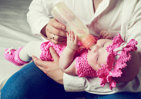 father feeding his four months old baby with milk from the bottle.