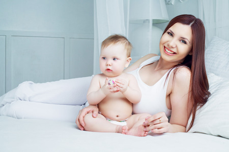 happy beautiful mother with her baby in bed at homeの写真素材