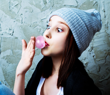 teenage girl with a bubble gum against old wallの写真素材