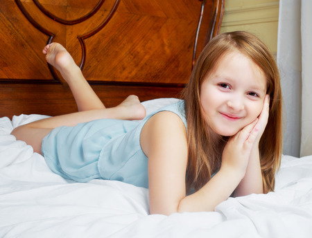 happy smiling girl in bed at homeの写真素材