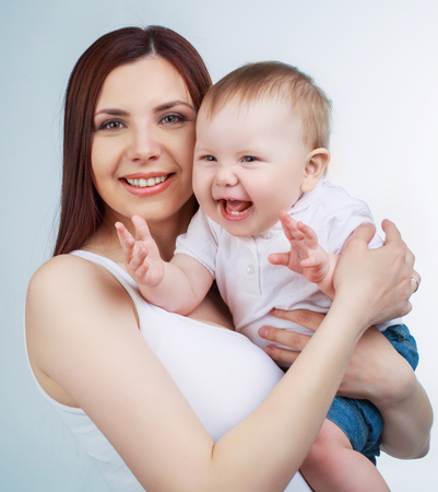 studio portrait of a happy mother holding her baby, isolated against white studio backgroundの写真素材