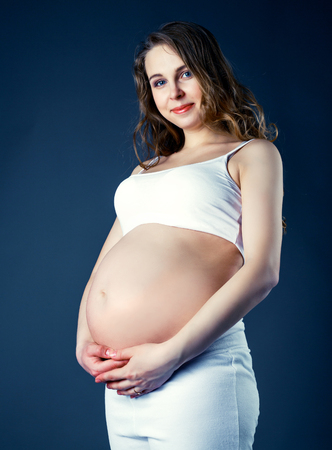 beautiful young pregnant woman, isolated against studio backgroundの写真素材