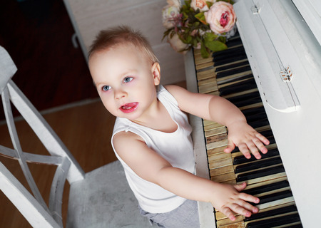 one year old baby boy playing an old pianoの写真素材