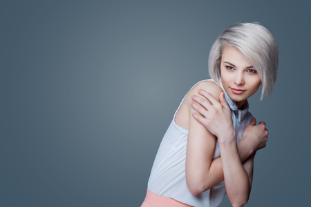 beautiful young blond woman with brown eyes against grey studio backgroundの写真素材