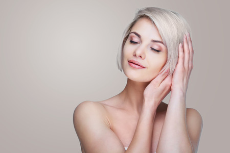 beautiful young blond woman with short blond hair against grey studio backgroundの写真素材