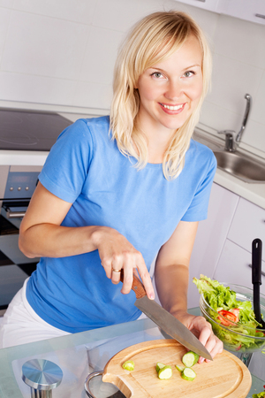 beautiful happy young woman cooking in the kitchen at homeの写真素材
