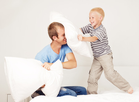 father and son having a pillow fight in bedの写真素材