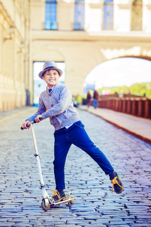 happy stylish boy with a scooter in the city streetの写真素材
