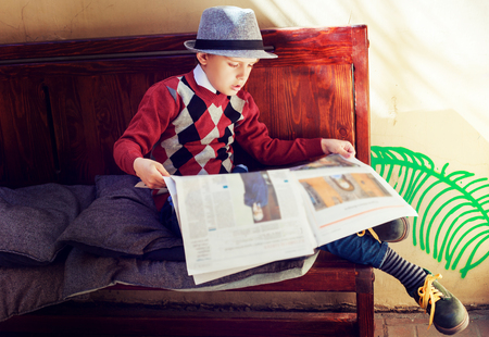 happy stylish boy with a newspaper on the benchの写真素材