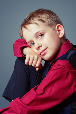 happy child wearing a shirt, isolated against grey backgroundの写真素材