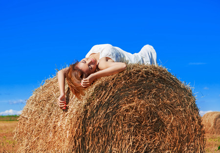 beautiful woman in the harvested  wheat field in august on a sunny dayの写真素材