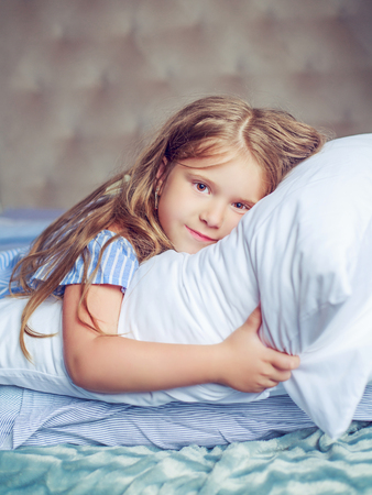 happy little girl relaxing in bed at homeの写真素材