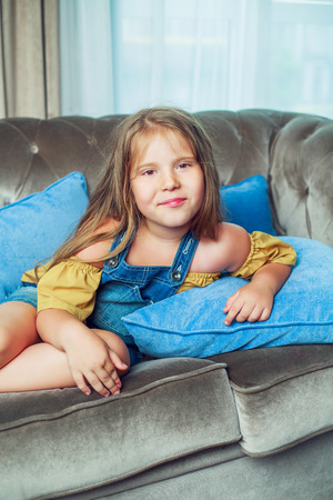 happy little girl on the sofa at homeの写真素材