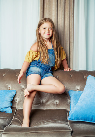 happy little girl on the sofa at homeの写真素材