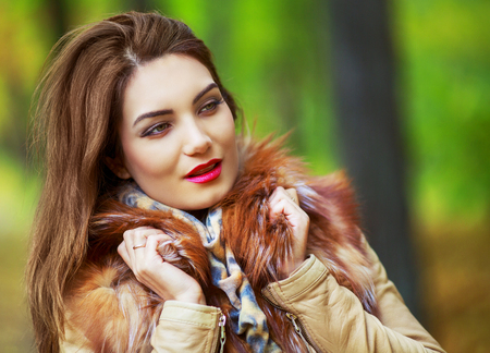 beautiful young woman holding yellow leaves in the autumn park outdoorの写真素材