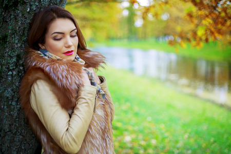 beautiful sad young woman   in the autumn park outdoorの写真素材