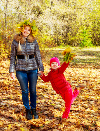 happy young beautiful mother and daughter in the autumn parkの写真素材