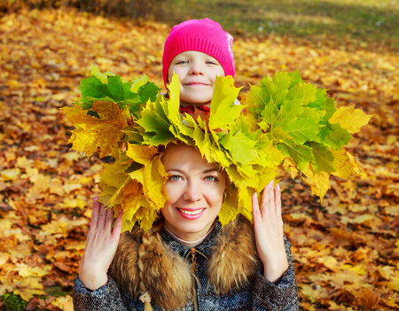 happy young beautiful mother and daughter in the autumn parkの写真素材