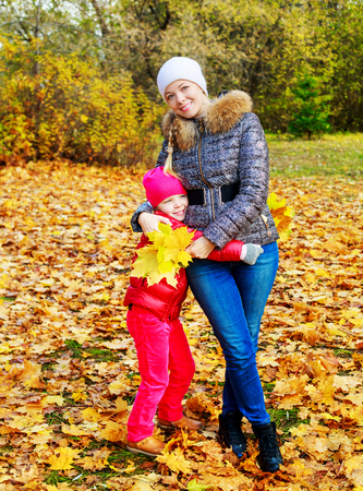 happy young beautiful mother and daughter in the autumn parkの写真素材