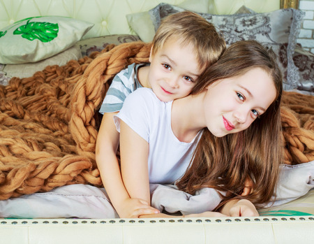 happy brother and sister relaxing in bed at homeの写真素材