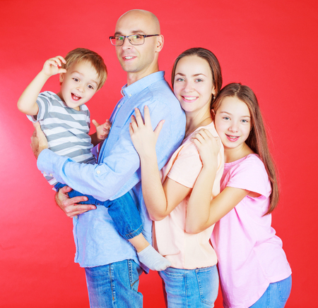 happy parents with two kids isolated against red backgroundの写真素材