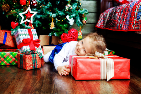 happy girl at home on the floor with Christmas tree and presentsの写真素材