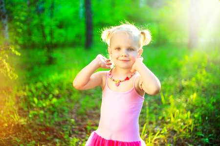 happy little girl wearing a pink dress,  in the summer parkの写真素材