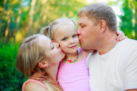 happy parents with their daughter outdoor in the summer parkの写真素材