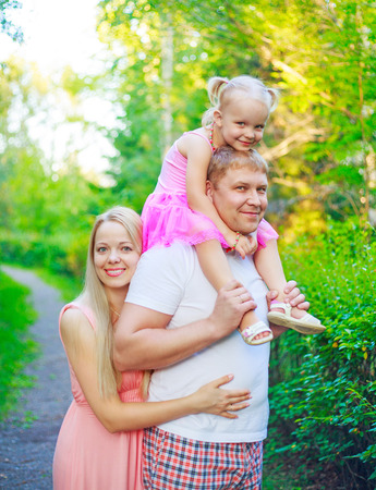 happy parents with their daughter outdoor in the summer parkの写真素材